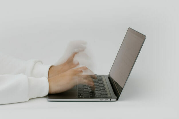 Hands typing on a laptop keyboard